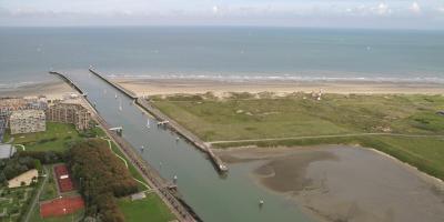 Luchtfoto van een waterweg die uitkomt in de Belgische kust.